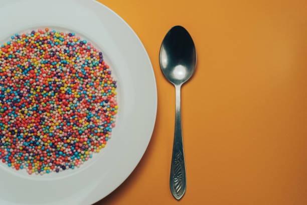 istock White plate with color preparations (vitamins, dyes, flavor enhancers, nutritional supplements, innovative technologies, candy sweets) on an orange background. 1143762053