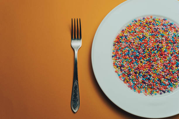 istock White plate with color preparations (vitamins, dyes, flavor enhancers, nutritional supplements, innovative technologies, candy sweets) on an orange background. 1143762116