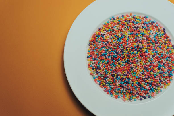 istock White plate with color preparations (vitamins, dyes, flavor enhancers, nutritional supplements, innovative technologies, candy sweets) on an orange background. 1143762136
