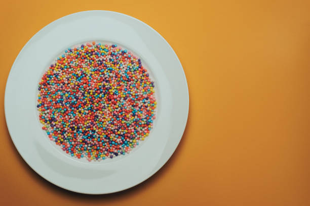 istock White plate with color preparations (vitamins, dyes, flavor enhancers, nutritional supplements, innovative technologies, candy sweets) on an orange background. 1143762202
