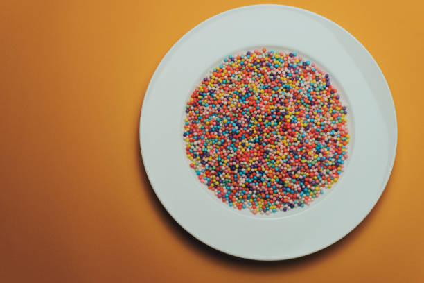 istock White plate with color preparations (vitamins, dyes, flavor enhancers, nutritional supplements, innovative technologies, candy sweets) on an orange background. 1143762229