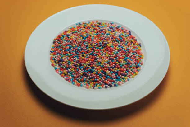 White plate with color preparations (vitamins, dyes, flavor enhancers, nutritional supplements, innovative technologies, candy sweets) on an orange background.