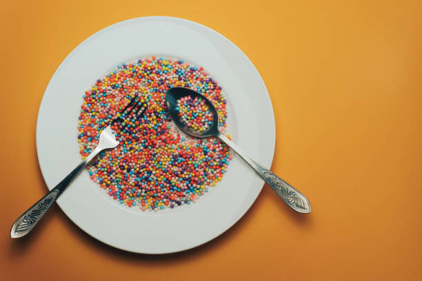 istock White plate with color preparations (vitamins, dyes, flavor enhancers, nutritional supplements, innovative technologies, candy sweets) on an orange background. 1143762348