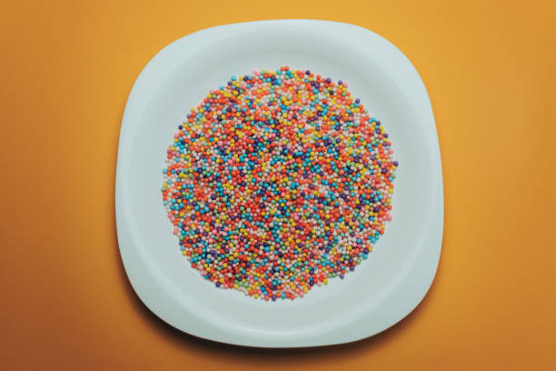 istock White plate with color preparations (vitamins, dyes, flavor enhancers, nutritional supplements, innovative technologies, candy sweets) on an orange background. 1143762359