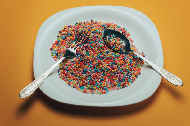 istock White plate with color preparations (vitamins, dyes, flavor enhancers, nutritional supplements, innovative technologies, candy sweets) on an orange background. 1143763047