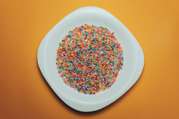 istock White plate with color preparations (vitamins, dyes, flavor enhancers, nutritional supplements, innovative technologies, candy sweets) on an orange background. 1143763076