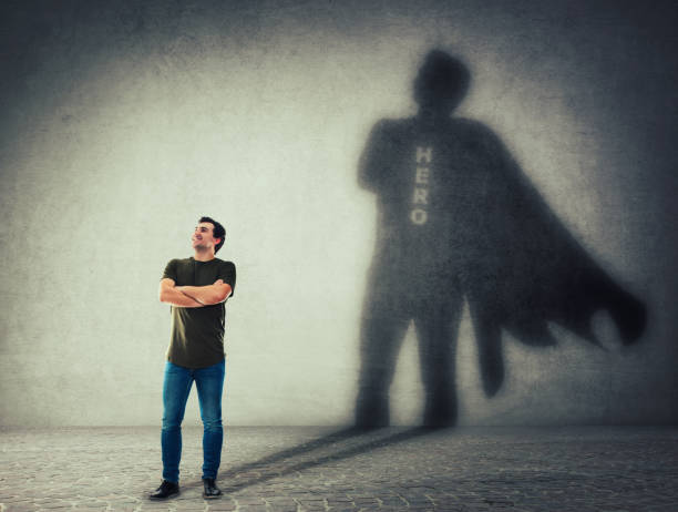 istock man casting a superhero with cape shadow on the wall 1143771396