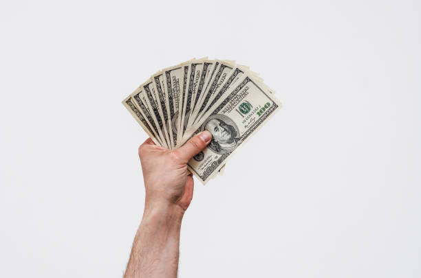 a mão do homem prende dólares americanos dinheiro. finanças, ganhos, crédito - currency paper currency wealth human hand - fotografias e filmes do acervo