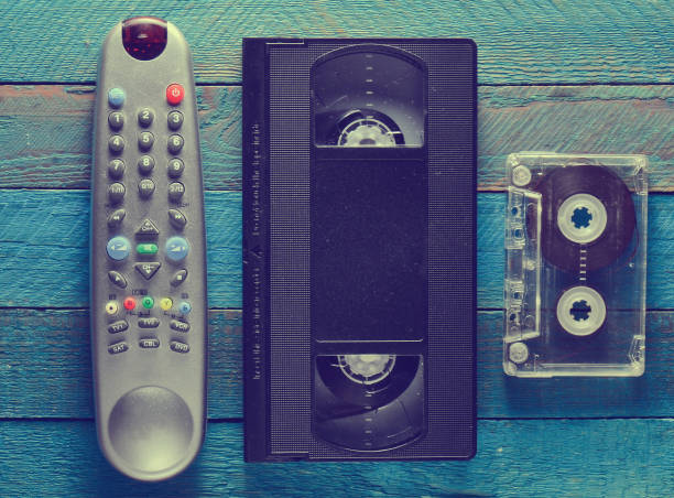 istock Video cassette, audio cassette, remote control on a blue wooden table. Retro media technology from the 80s. Copy space. Top view. 1143773254