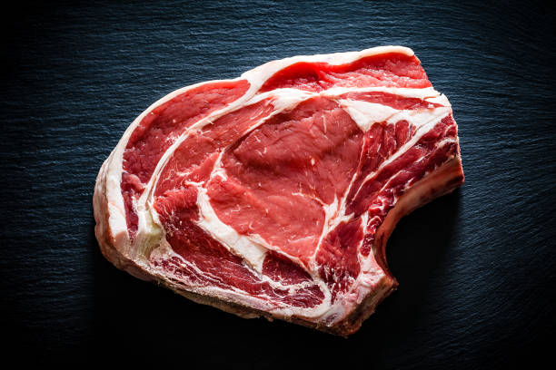 Raw rib steak shot from above on black background