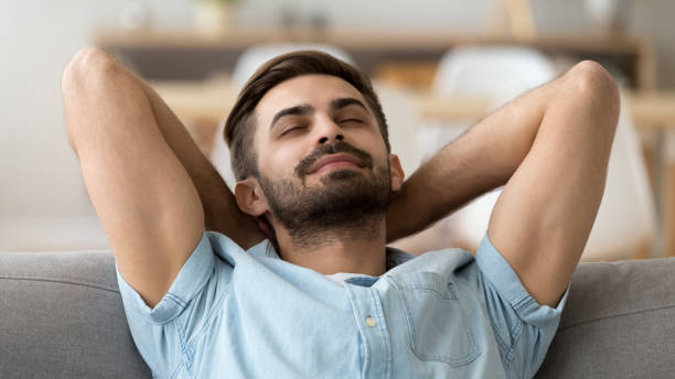 istock Calm peaceful man relaxing with closed eyes leaning back on sofa 1143775410