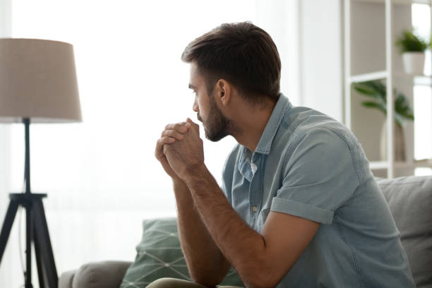 사려깊은 심각한 남자 집에서 소파에 앉아, 생각에 손실 - men thinking contemplation pensive 뉴스 사진 이미지