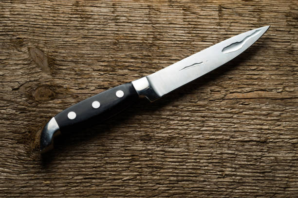 istock Kitchen knife with water drops on a background of rough wood texture 1143777458