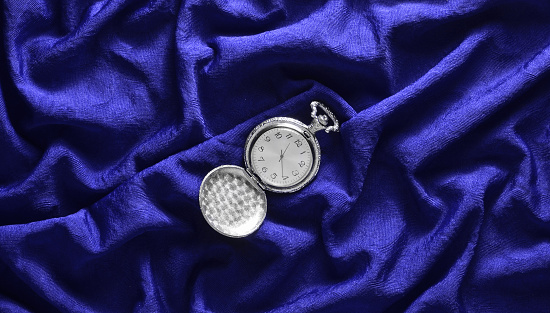 Antique  pocket watch on blue silk background. Top view.