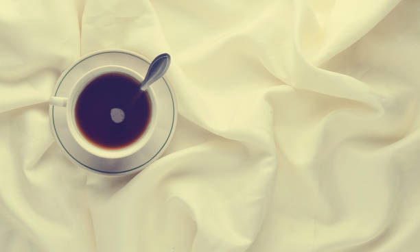 istock A cup of tea on the bed sheet. Top view. Minimalism trend. 1143777950