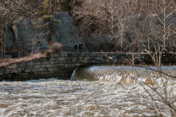 Man watching Blackstone River current in Cumberland, Rhode Island Cumberland, Rhode Island, USA - February 15, 2008: Man contemplating the turbulent water flowing down the Blackstone River on a winter afternoon rhode island photos stock pictures, royalty-free photos & images