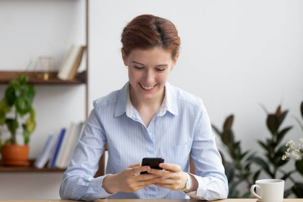 istock Smiling businesswoman using mobile phone at workplace during break 1143790700