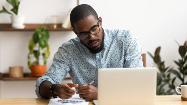 istock Focused African American businessman using laptop, writing notes 1143790701
