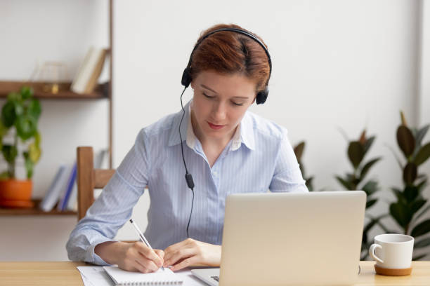 istock Focused woman in headphones using laptop, writing notes 1143790720