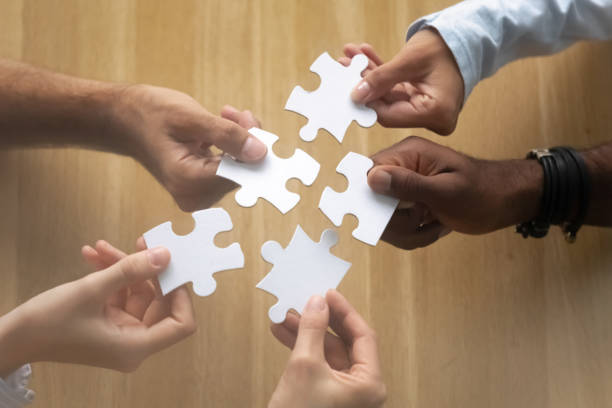 istock Hands of diverse team members assembling jigsaw puzzle close up 1143790833