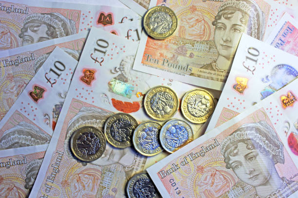 Coins & Banknotes Close-up of pound coins on ten pound notes. one pound coin uk coin british currency stock pictures, royalty-free photos & images