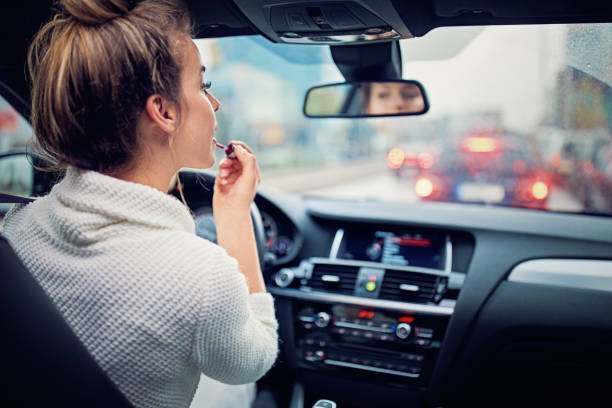 chica joven está poniendo lápiz labial en el atasco de tráfico en el día lluvioso - driving car distracted accident fotografías e imágenes de stock