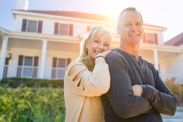 Attractive Middle-aged Couple In Front Of Their House Attractive Middle-aged Couple In Front Of Their House. for sale sign photos stock pictures, royalty-free photos & images