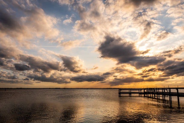 Wooden wharf over Banana river situated on the east coast of Florida with a cloudy sky at sunset.