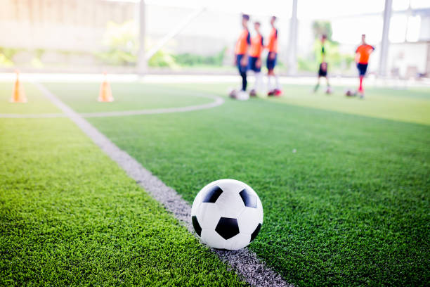 istock football on green artificial turf with blurry soccer team training 1143821912