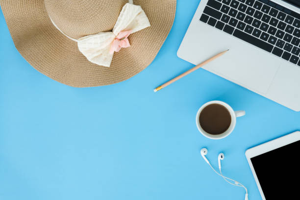 istock Office desk working space - Flat lay top view copy space of working space with laptop, summer hat, coffee and smart tablet placing on blue pastel background. Pastel blue color background space concept 1143824059