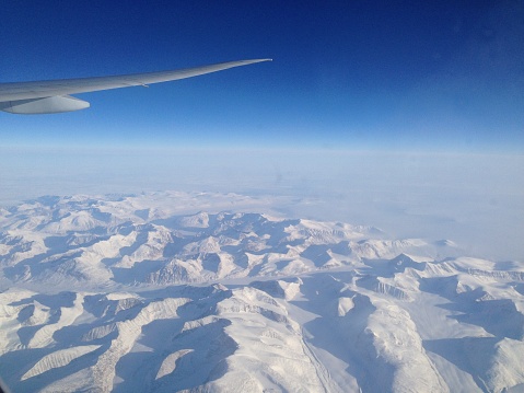 View of the snow mountains and glaciers of Greenland from an airplane window on a flight from New York to Hongkong