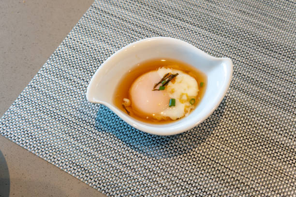Onsen egg in Japanese style bowl on silver woven table mat.