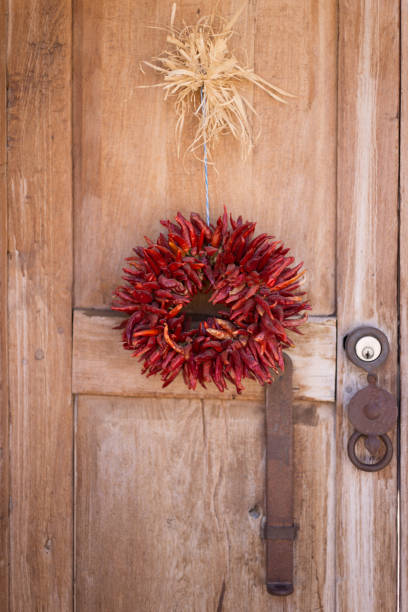 santa fe style: chili pepper ristra wreath auf holztür - wreath chili pepper pepper ristra stock-fotos und bilder