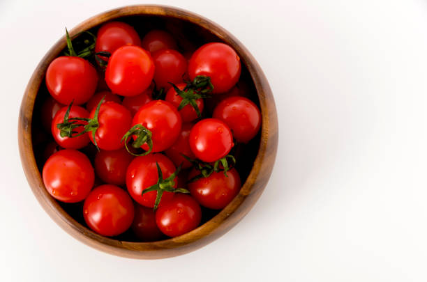 istock Fresh red cherry tomatoes in wooden round bowl on white background 1143855820