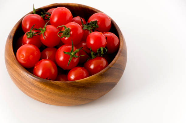 istock Fresh red cherry tomatoes in wooden round bowl on white background 1143856056