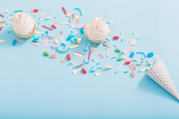 istock birthday hat with confetti and cupcake on blue paper background 1143856985