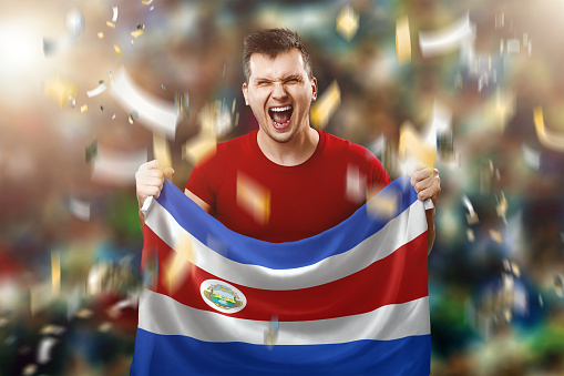 Costa Rica is a fan, a fan of a man holding the national flag of Costa Rica in his hands. Soccer fan in the stadium.