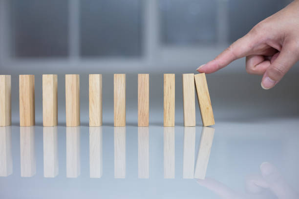 istock Hand pushing a dominoes concept. 1143864531