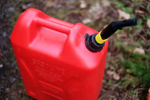 A 5-gallon gas can in use along a forest road