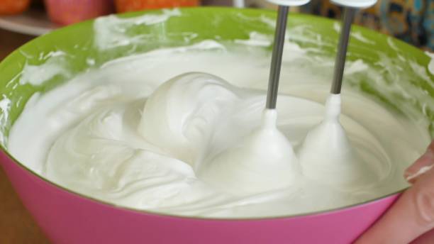 istock Kitchen mixer whips cream custard pastry whisk rotates rapidly. Food processor beat the eggs white egg whites into a thick foam. Kitchen machine in operation 1143874575