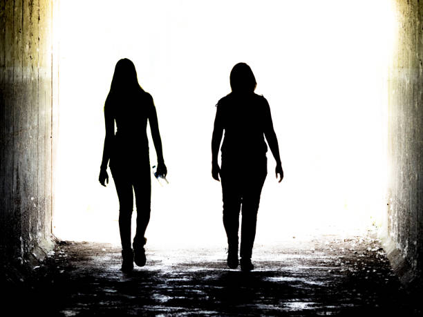 2 people walking into the light stock photo
