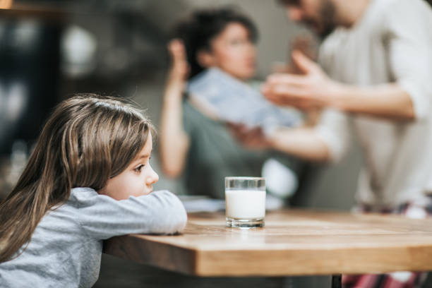 Why are they arguing? Little girl feeling sad while her parents are arguing in the background. arguing couple divorce family stock pictures, royalty-free photos & images