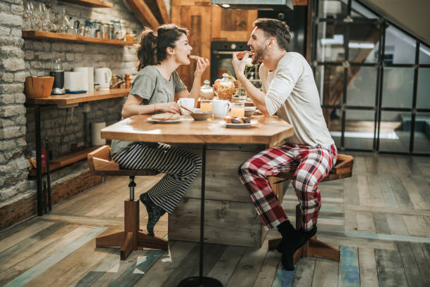 istock Young happy couple having fun while eating sandwiches for breakfast in the kitchen. 1143890266
