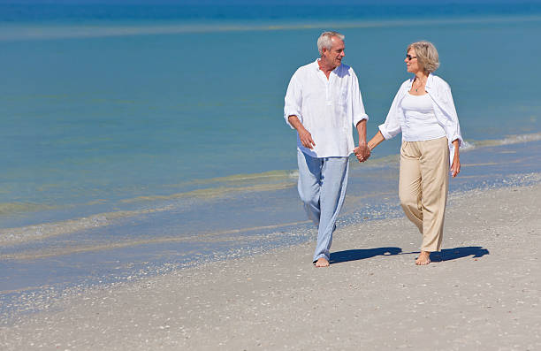 istock Joyful senior couple walking down beach hand in hand 114389027