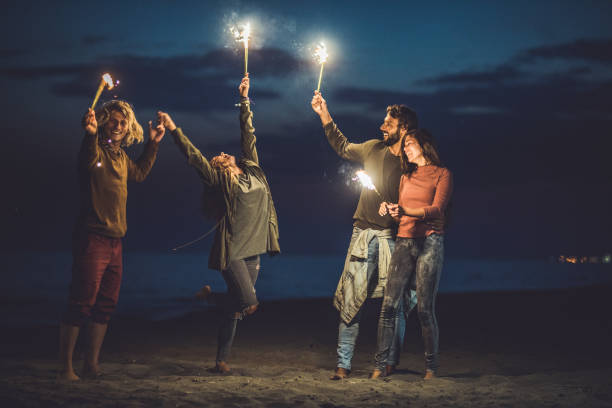 istock Happy couples having fun with flaming torches on the beach by night. 1143896687