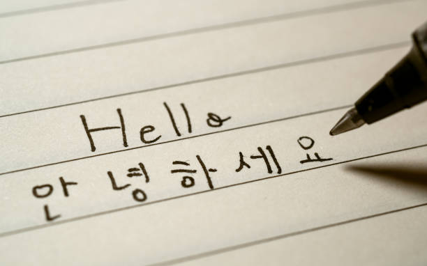 istock Beginner Korean language learner writing Hello word Annyeonghaseyo in Korean characters on a notebook close-up shot 1143896723
