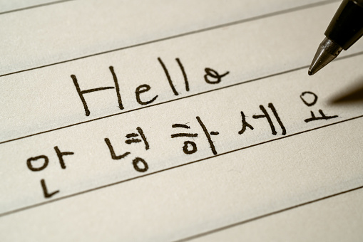 Beginner Korean language learner writing Hello word in Korean characters on a notebook macro shot