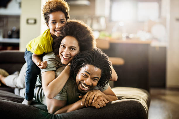 istock Happy black family making human pyramid on sofa at home. 1143896883