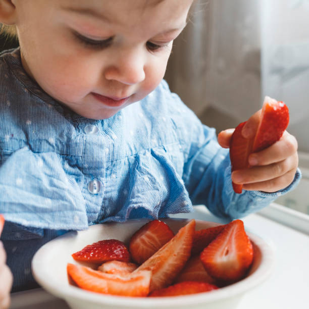 istock Curious baby playing with strawberries 1143897982