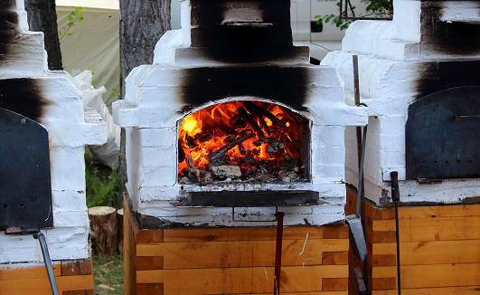 Burning fire in the traditional white russian stove. Food court at the annual International Festival of Music and Crafts World of Siberia or FestMirSibiri